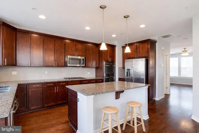 a kitchen with stainless steel appliances granite countertop a sink a stove and a refrigerator