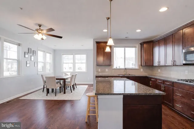 a kitchen with stainless steel appliances granite countertop hardwood floor sink stove dining table and chairs