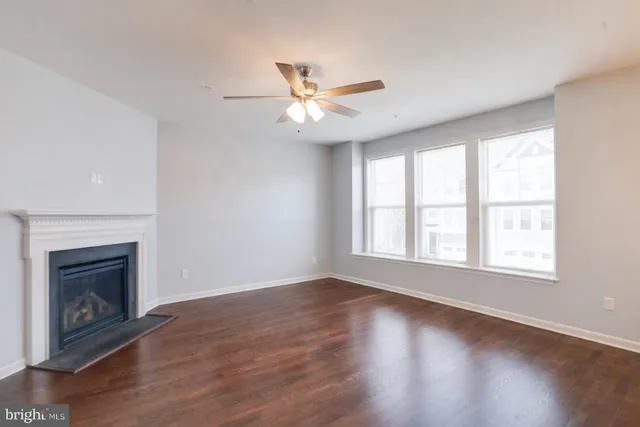 an empty room with wooden floor fireplace and windows