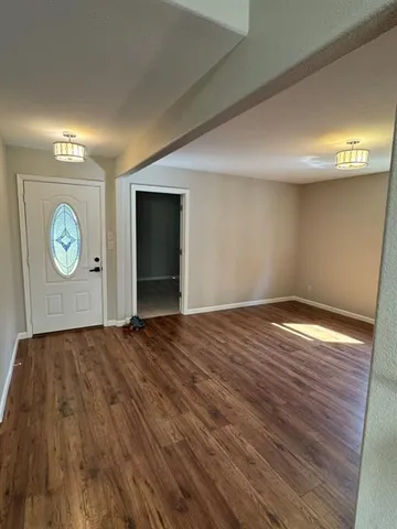 an empty room with wooden floor fireplace and windows