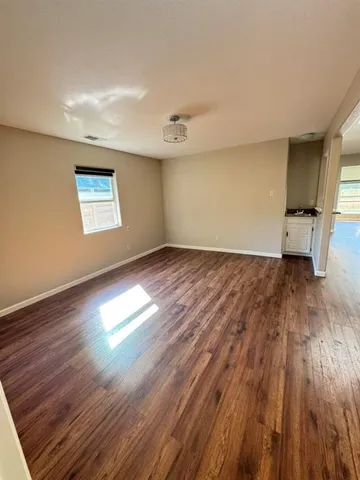 an empty room with wooden floor a ceiling fan and a fireplace