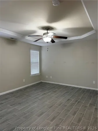 an empty room with wooden floor chandelier fan and windows