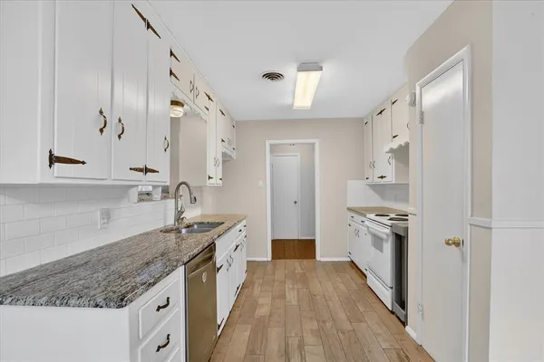 a kitchen with granite countertop a sink stove and refrigerator