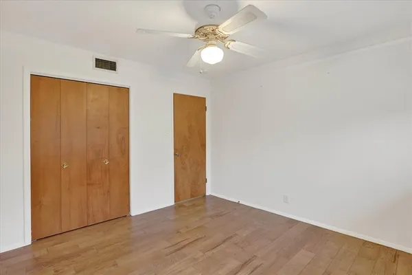 an empty room with wooden floor and ceiling fan