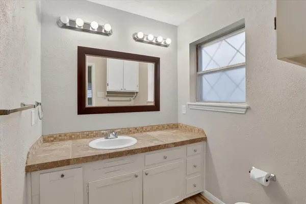 a bathroom with a granite countertop sink two mirror and window