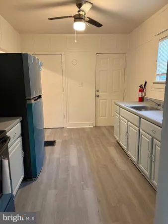a view of a kitchen with a sink and dishwasher a refrigerator with wooden floor