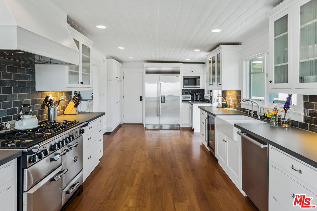 7163 Birdview Avenue Malibu, CA 90265 - Photo 9 of 22 a kitchen with stainless steel appliances a stove a sink dishwasher a refrigerator and a stove with wooden floor