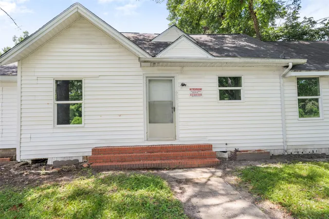 a white house with a small yard and large trees