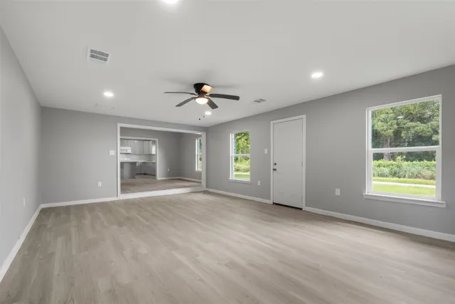 a view of an empty room with window and wooden floor