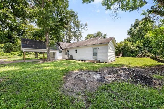 a backyard of a house with plants and large tree