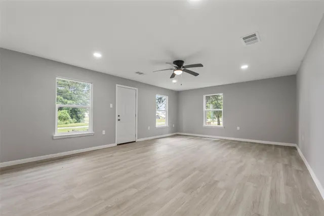 a view of an empty room with a window and wooden floor