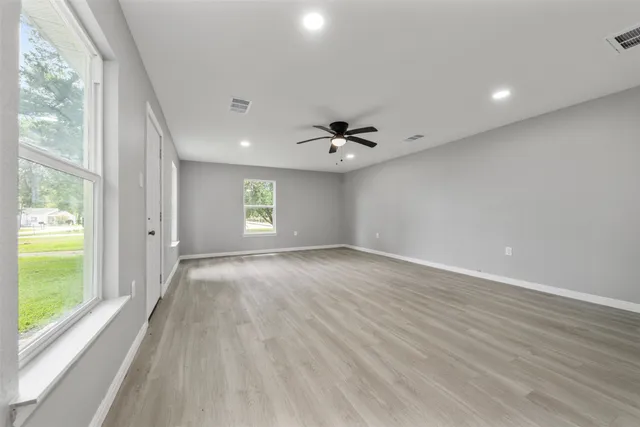 a view of an empty room with a window and wooden floor