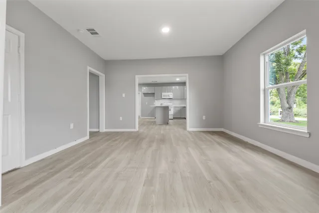 a view of an empty room with a window and wooden floor