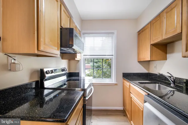 a kitchen with granite countertop a sink cabinets and stainless steel appliances