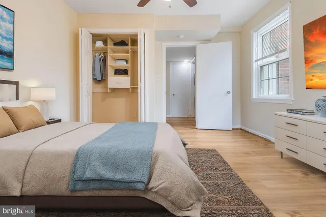 an empty room with wooden floor chandelier fan and windows