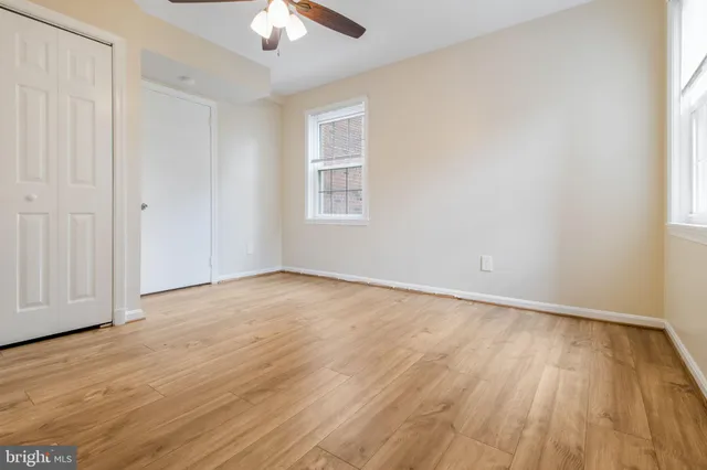 an empty room with wooden floor chandelier fan and windows