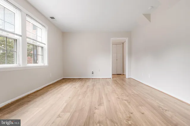 an empty room with wooden floor and windows