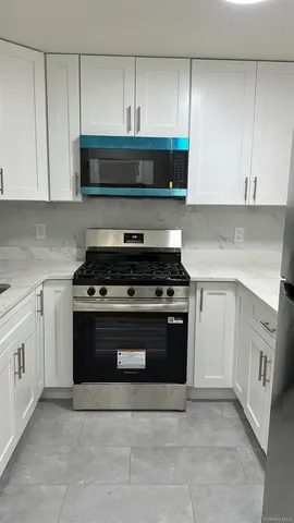 a kitchen with stainless steel appliances granite countertop a stove a microwave and a white cabinets