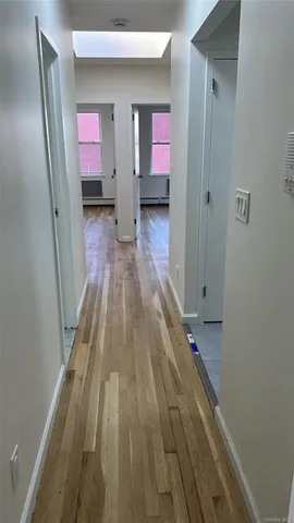 a view of a hallway with wooden floor and red carpet
