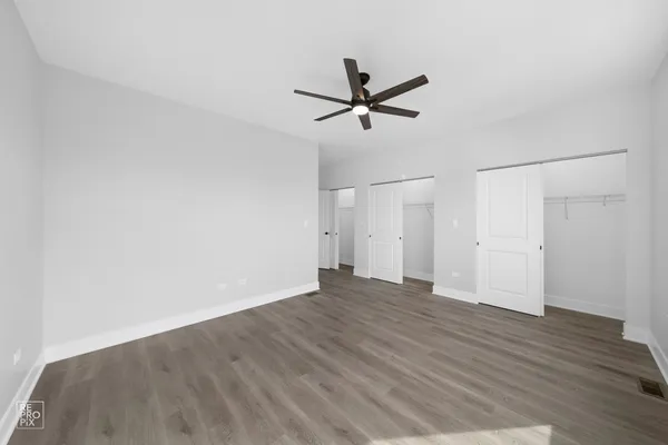 a view of empty room with wooden floor and ceiling fan