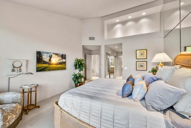 a bedroom with a large bed and a potted plant