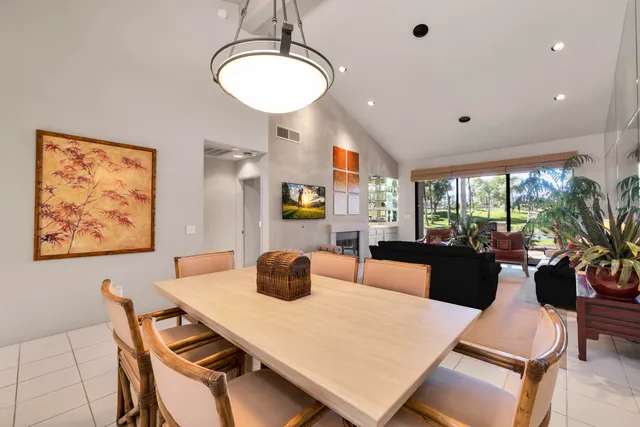 a view of a dining room and livingroom with furniture wooden floor a rug a flat screen tv a rug and a chandelier