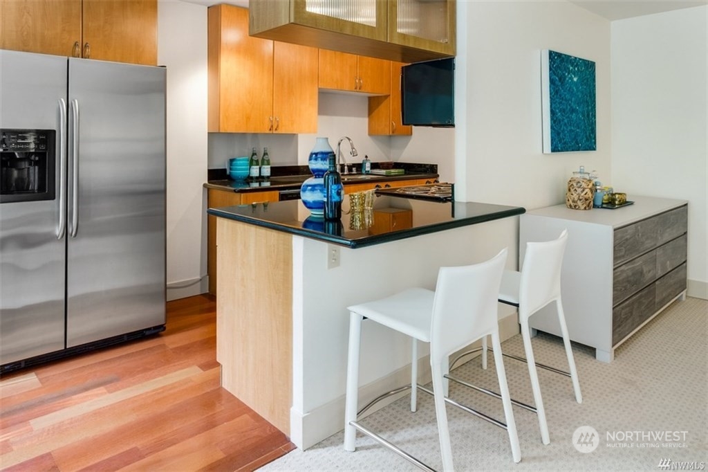 1105 Spring Street, Unit 305 Seattle, WA 98104 - Photo 10 of 25 a kitchen with stainless steel appliances kitchen island granite countertop a refrigerator and a stove