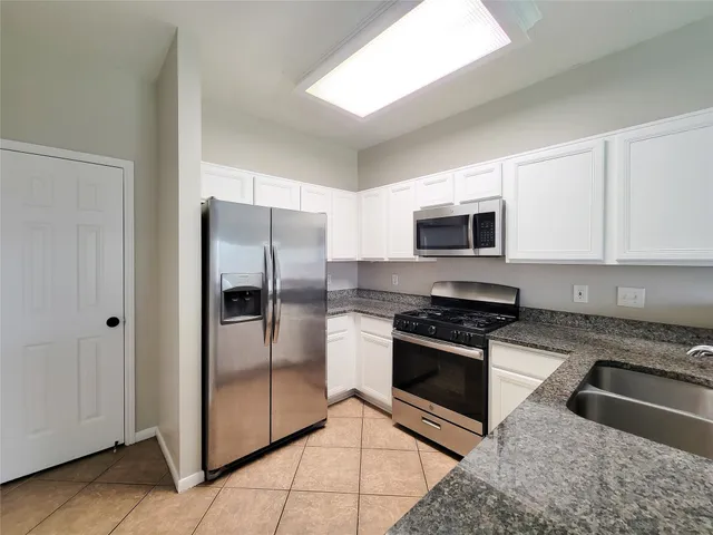 a kitchen with granite countertop a refrigerator and a stove top oven
