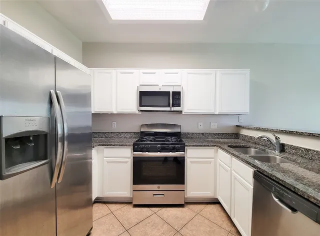 a kitchen with granite countertop a stove sink and refrigerator