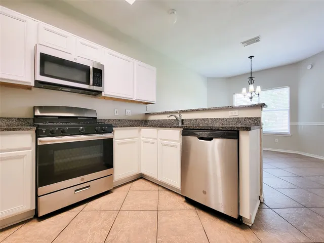 a kitchen with granite countertop a stove top oven microwave and cabinets