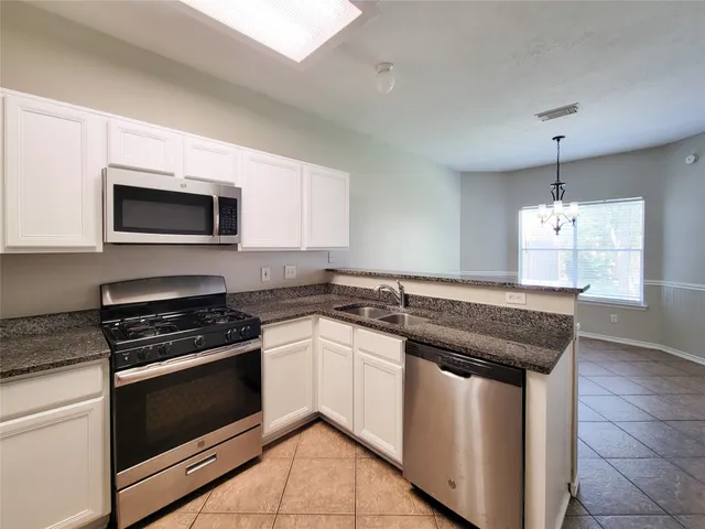 a kitchen with granite countertop a stove sink and microwave