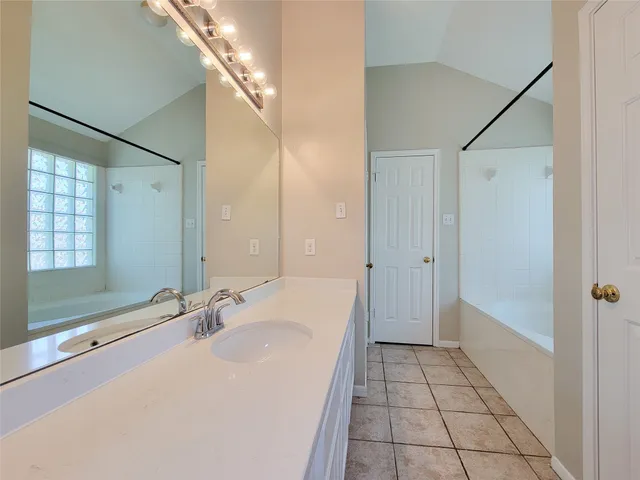 a bathroom with a granite countertop sink a mirror and a bathtub