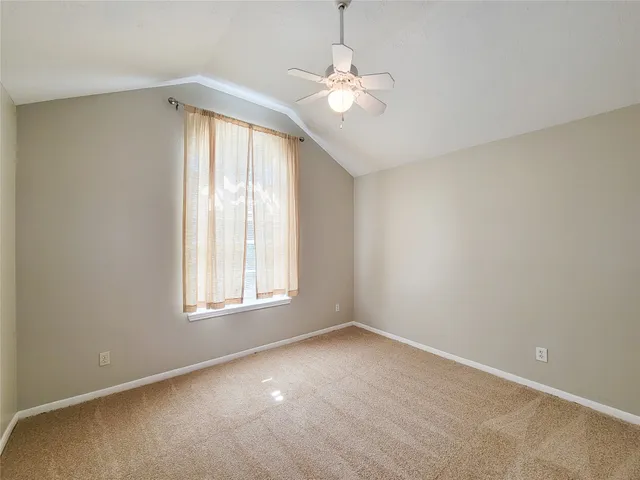 an empty room with windows and chandelier fan
