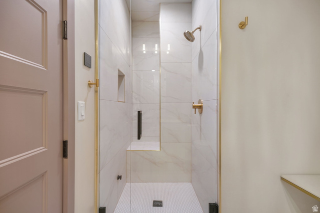 10646 North Reflection Ridge Hideout, UT 84036 - Photo 25 of 43 Tiled shower with glass enclosure, gold-finish fixtures, built-in bench, and recessed shelf