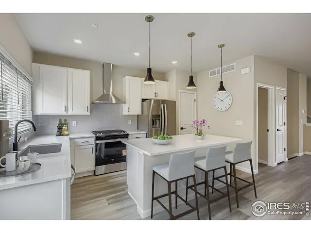 a kitchen with stainless steel appliances kitchen island granite countertop a sink a stove a refrigerator and white cabinets