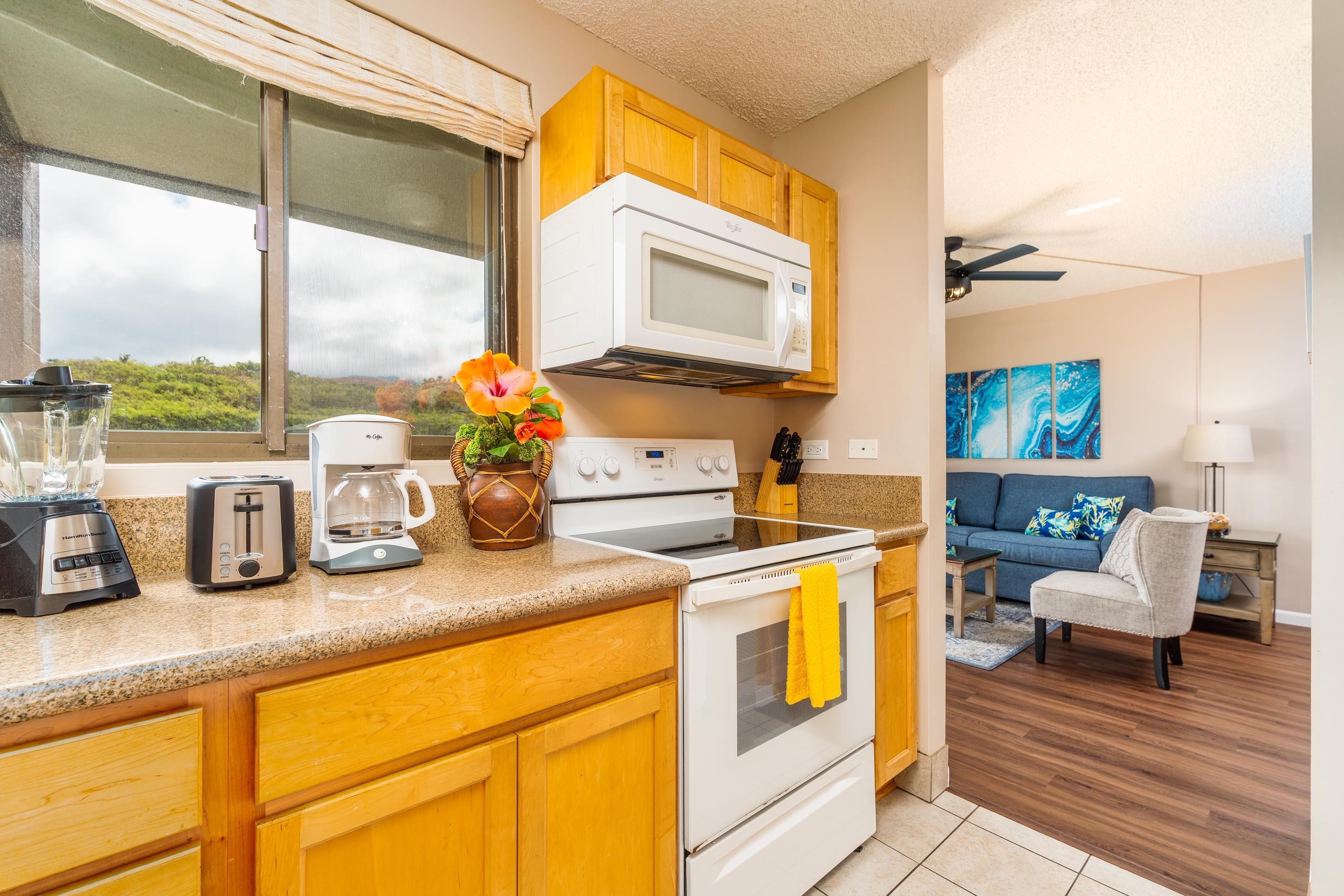 4310 Lower Honoapiilani Road, Unit 418 Lahaina, HI 96761 - Photo 9 of 31 a kitchen with sink a window and chairs