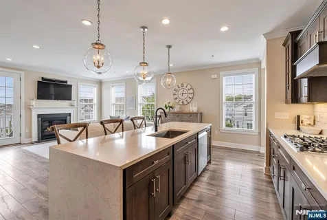 a large kitchen with stainless steel appliances granite countertop a sink a stove and a wooden floors