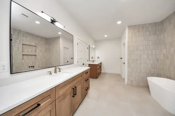 a bathroom with a double vanity sink mirror and bathtub