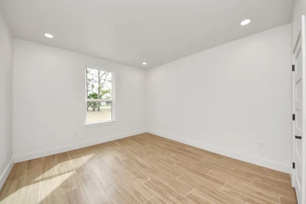 an empty room with wooden floor and windows