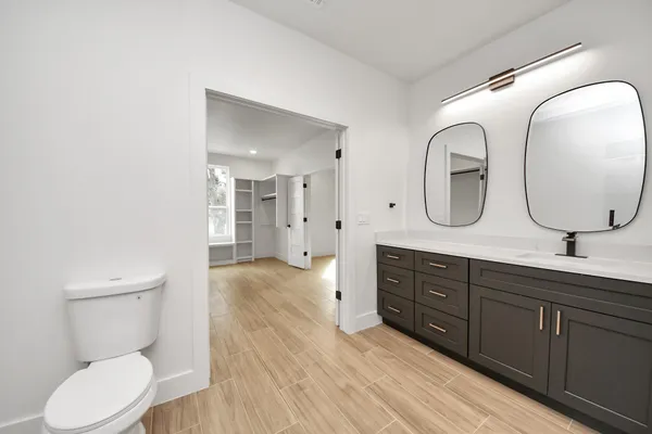 a spacious bathroom with a double vanity sink a toilet and a mirror