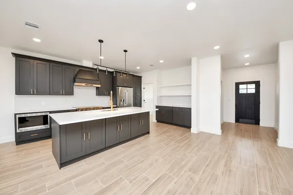a large kitchen with stainless steel appliances kitchen island a large counter top and a stove top oven