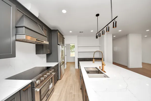 a large kitchen with stainless steel appliances kitchen island a large counter top a stove a chimney a sink and cabinets