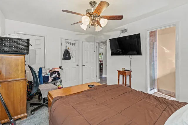 a bedroom with a bed a flat screen tv and a chandelier