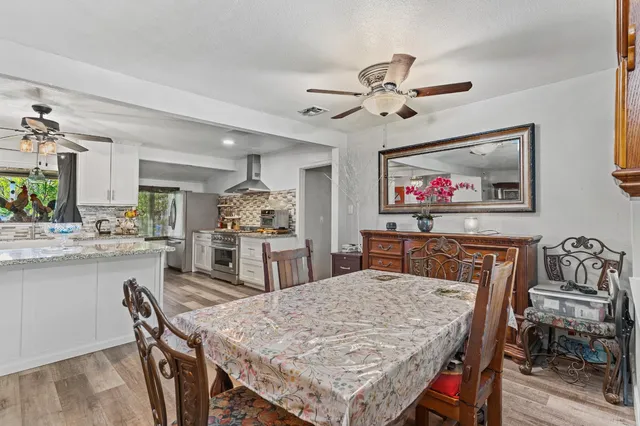 a dining hall with stainless steel appliances granite countertop a stove top oven a dining table and chairs with wooden floor