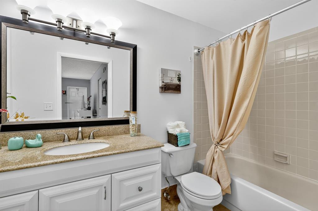 13930 Nesting Way, Unit C Delray Beach, FL 33484 - Photo 26 of 41 a bathroom with a granite countertop sink toilet a large mirror a bathtub and shower