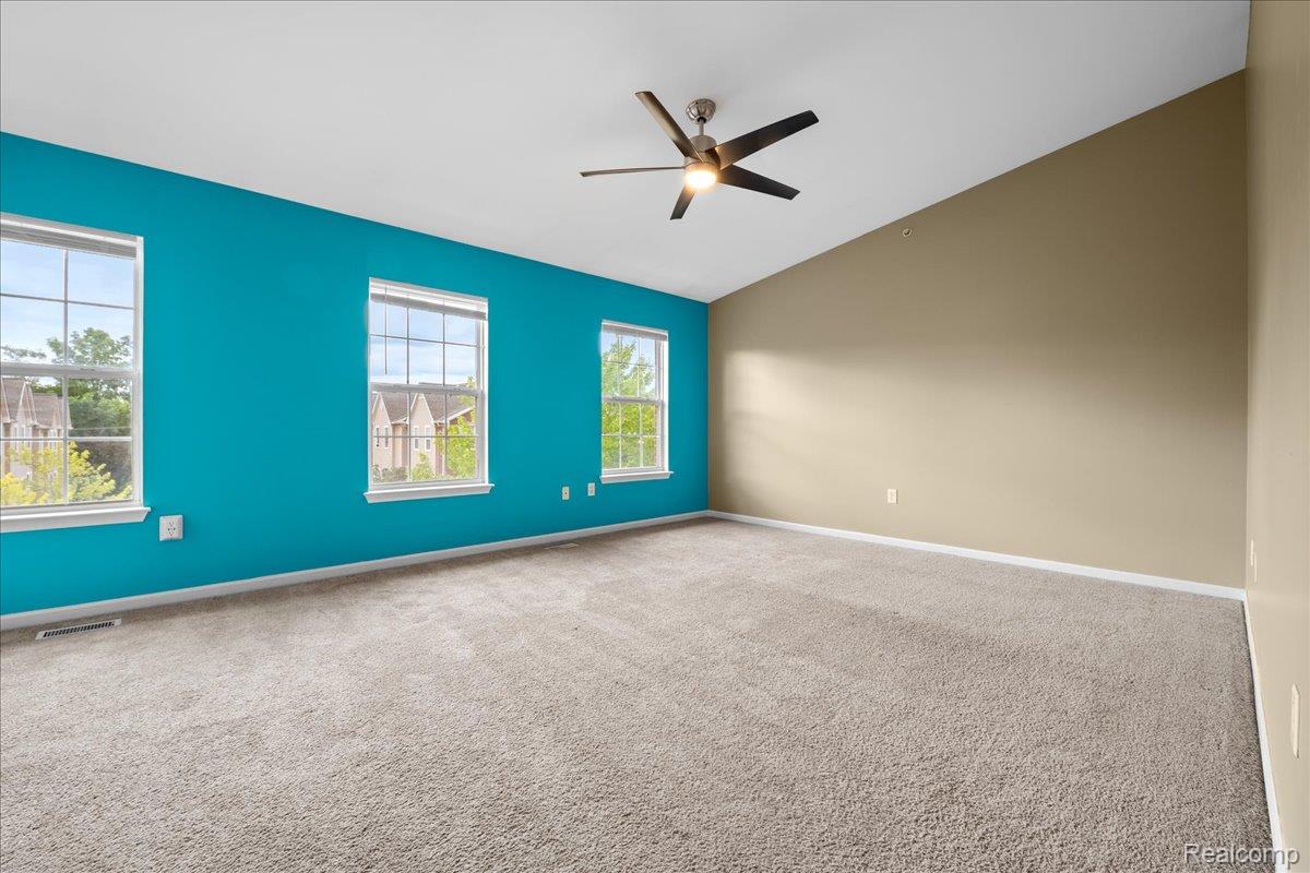 22684 Goddard Road Taylor, MI 48180 - Photo 14 of 29 Spacious interior room featuring a vaulted ceiling with a ceiling fan, three windows providing natural light, and plush carpet flooring