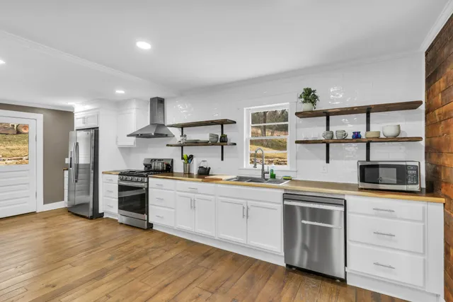 a kitchen with stainless steel appliances white cabinets and wooden floor