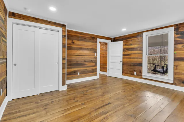 a view of an empty room with a window and wooden floor