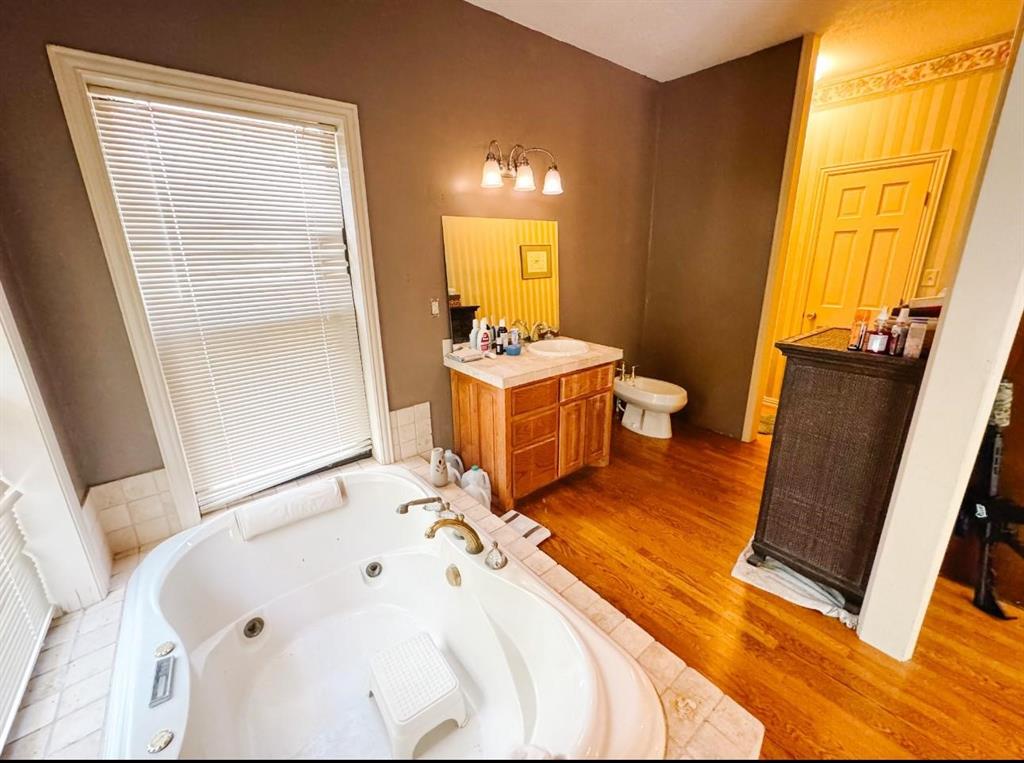 13610 Hwy 183 Rising Star Tx 76471 Rising Star, TX 76471 - Photo 13 of 39 Full bathroom featuring vanity, a tub with jets, a bidet, and wood finished floors