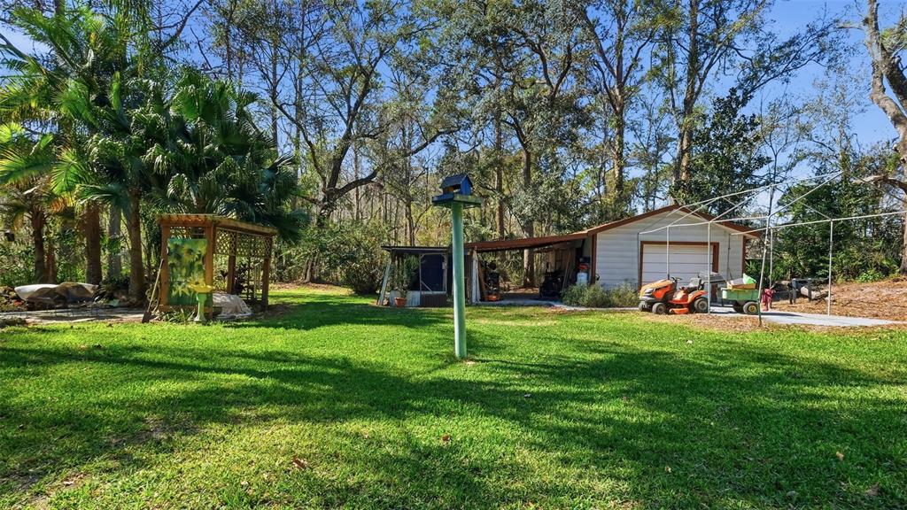 10565 Bessemer Street New Port Richey, FL 34654 - Photo 34 of 72 a view of a white house in front of a big yard with large trees